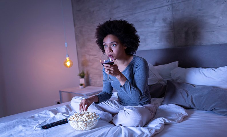 Lady drinking wine and eating popcorn